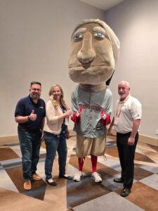 Three people standing with the Washington DC inspired mascot 